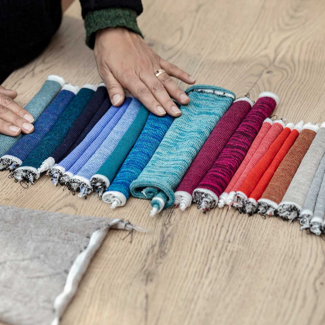 Alpaka Stoffe - Die Geschichte der Alpakawolle Bunte Alpaka Stoffrollen in verschiedenen Farbtönen, sorgfältig auf einem Tisch angeordnet.