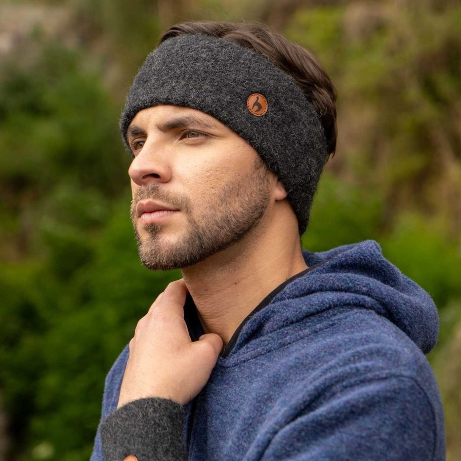 Mann mit Alpaka Stirnband und blauem Alpaka Hoodie, betrachtet nachdenklich die Natur.