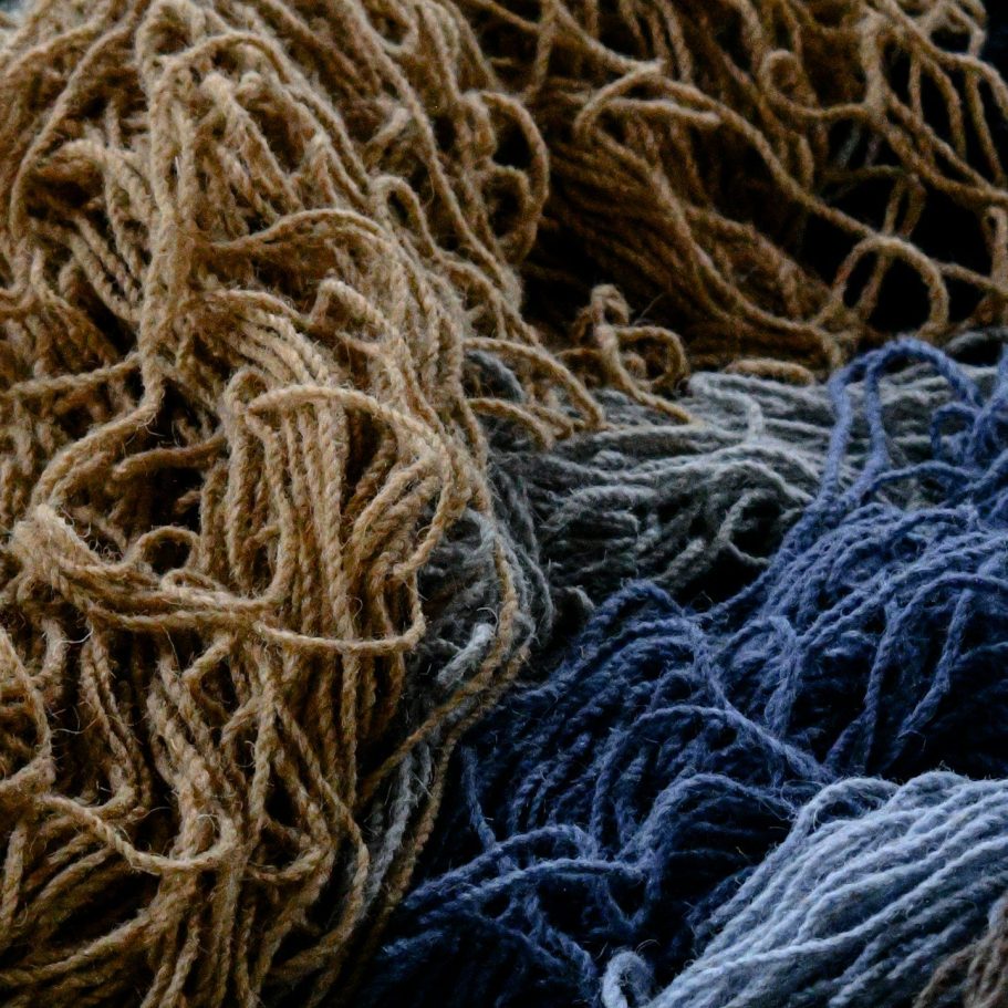 Alpaka Wolle - Alpaka oder Merino – Die wichtigsten Unterschiede Eine Ansammlung von verknäueltem Alpaka Garn in Braun-, Grau- und Blautönen.