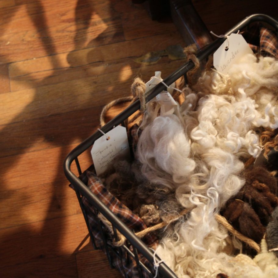Alpaka Wolle - Alpaka oder Merino – Die wichtigsten Unterschiede Ein Korb mit verschiedenen Wollsorten, darunter lockige und glatte Fasern.