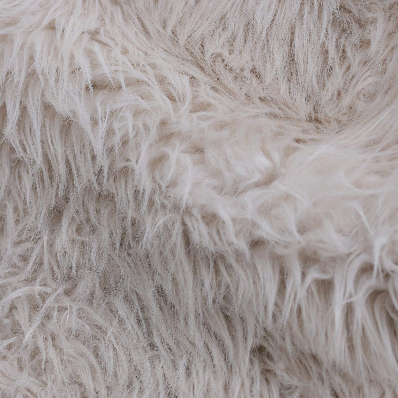 Flauschige, beigefarbene Alpaka Wolle mit langen, weichen Haaren.